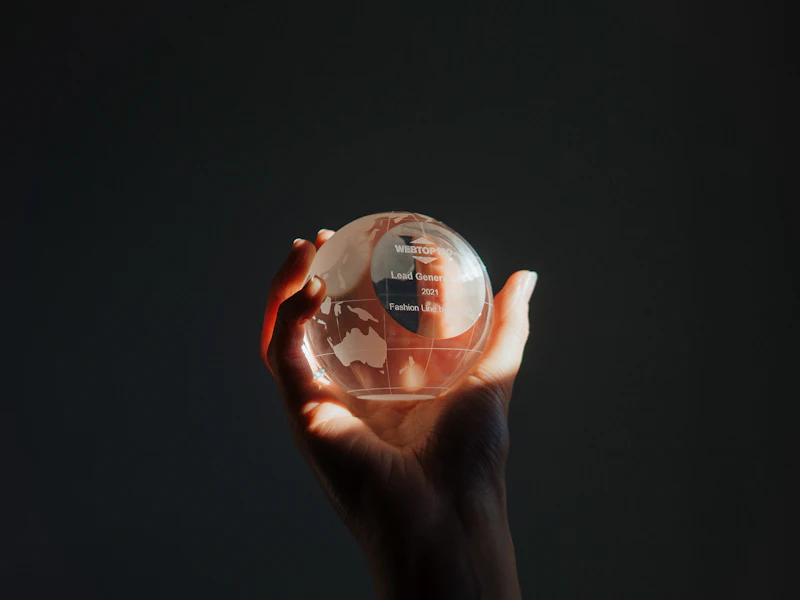 A hand holding a clear crystal globe