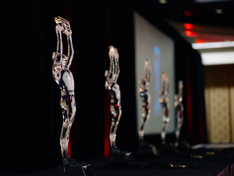 Clear crystal figure awards lined up on a dark stage