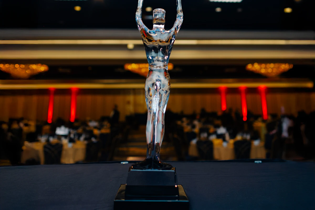 A clear crystal figure award presented on stage at a corporate awards gala