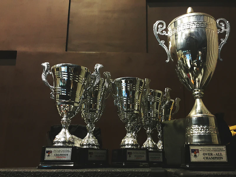 Silver and gold metal trophy cups on a wooden surface