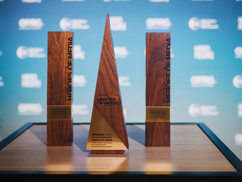 Three wooden awards with engraved plates on a table